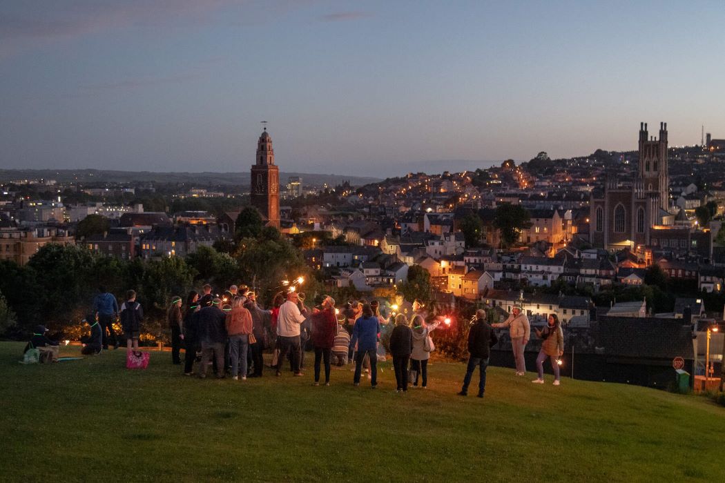 A group of people at Patricks Hill in Cork City, holding lights as the sun sets